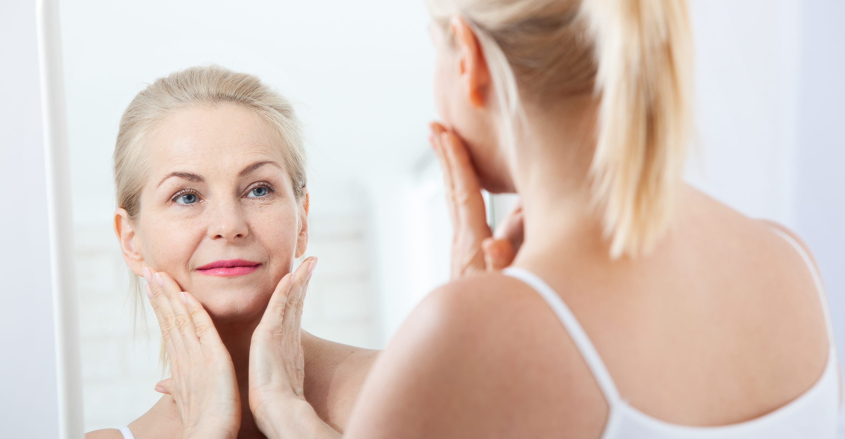 woman looking at her skin in the mirror 